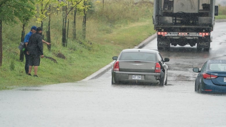 Cars driving through large floods on the road. 