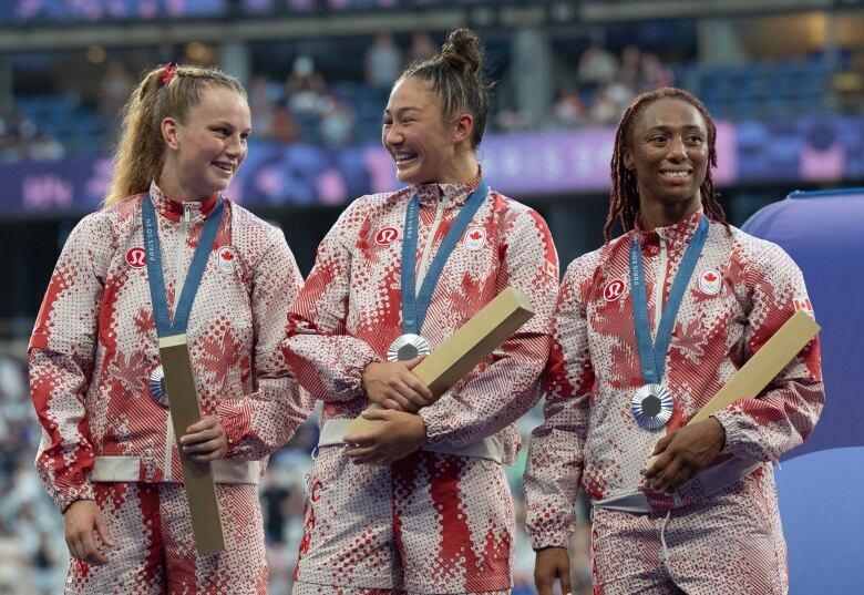 Women's sevens rugby player Charity Williams, right, Florence (Flo) Symonds, middle, and Carissa Norsten, left, stand on the podium after winning silver at the Summer Olympics in Paris, Tuesday, July 30, 2024. 