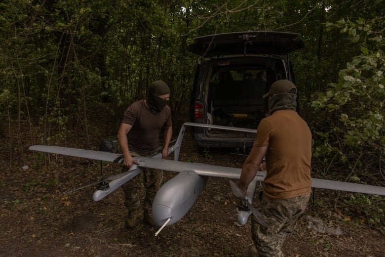 Ukrainian miliary members carry a reconnaissance drone at a position in Ukraine's Sumy region, near the Russian border, on Sunday.