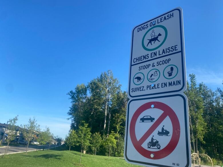 A sign tells dog owners to stoop and scoop. The sign includes pictographs of a pooping dog, a shovel and bag, followed by an open toilet.  