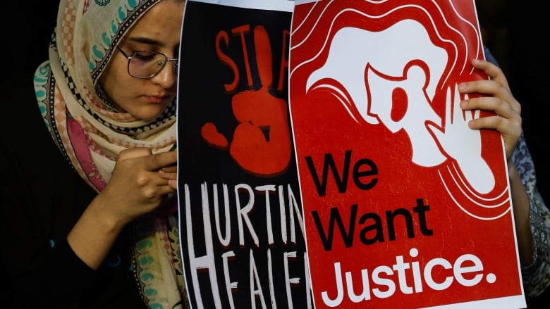 Two women hold signs that  say we want justice