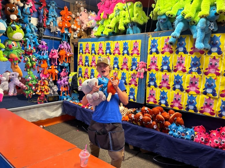 Boy holding stuffed animals at carnival game.