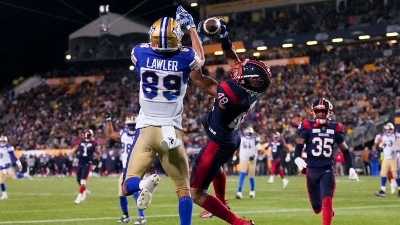 A football player attempts to a catch a ball before a player on the opposing team snatches it. 