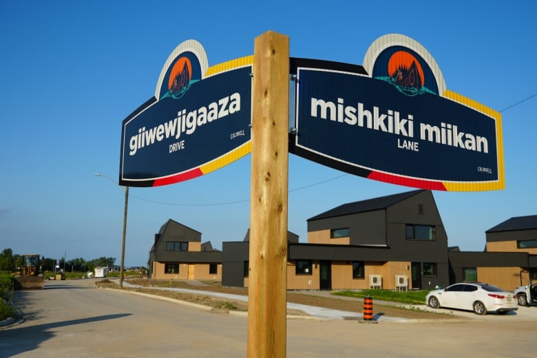 Street signs show Indigenous names, with new homes sitting in the background. 