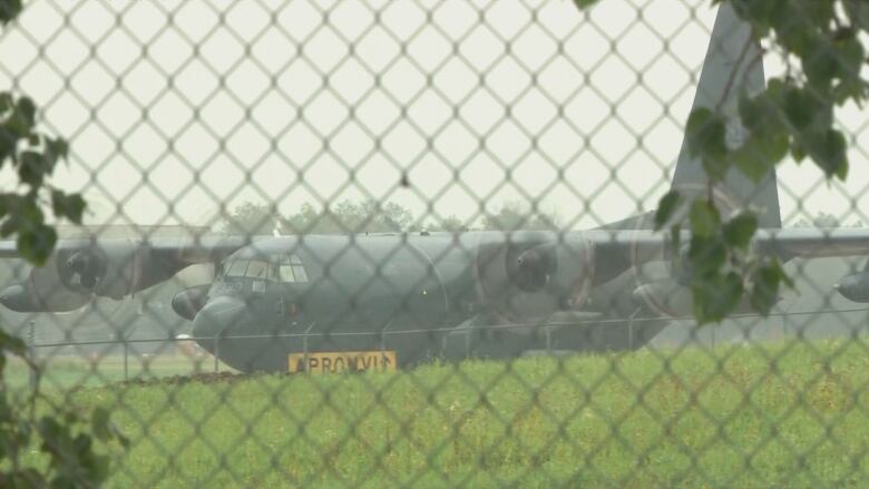 A military airplane behind a fence.