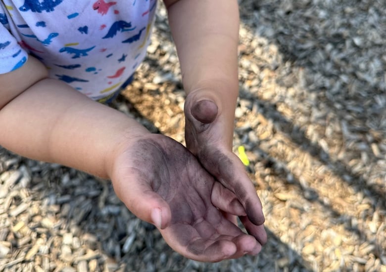 Child's hands with black on them