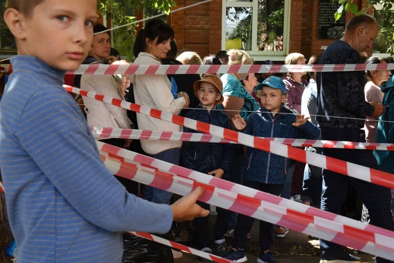 People evacuated from fighting between Russian and Ukrainian forces queue to receive humanitarian aid at a distribution center in Kursk, Russia on Monday, Aug. 12, 2024.