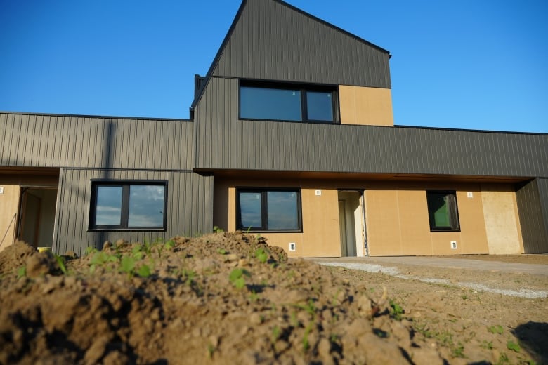 Dirt sits in front of a newly built home that still needs a door attached.