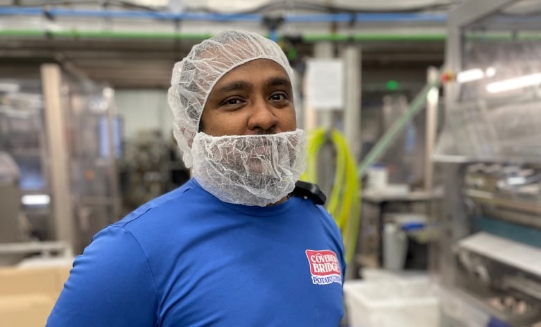 a man in a hair net and beard net stands in a warehouse