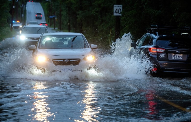 Cars drive slowly through flooded streets in Sainte-Anne-de-Bellevue on the island of Montreal after heavy rains hit the area on Friday, August 9, 2024.