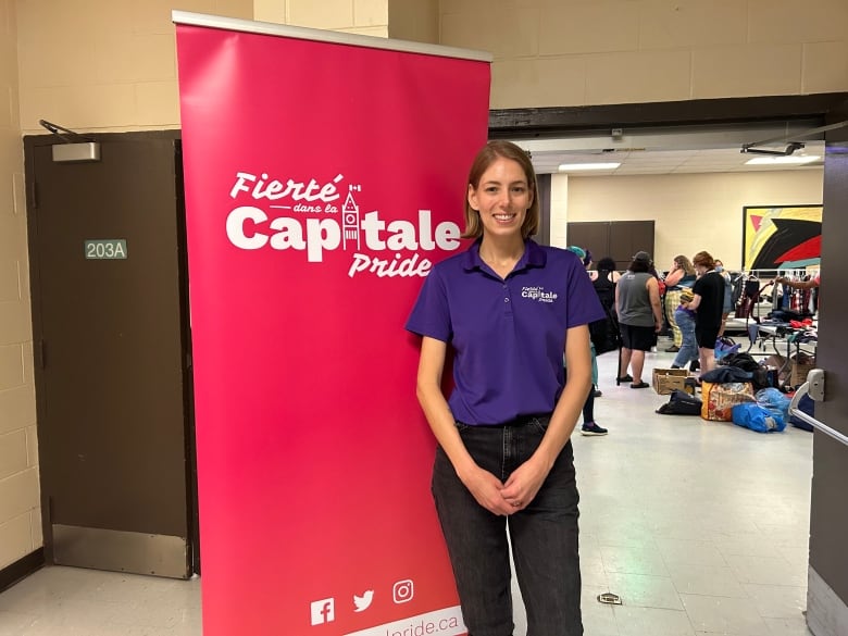 Callie Metler stands in front of a Capital Pride banner, just outside the organization's clothing swap event.