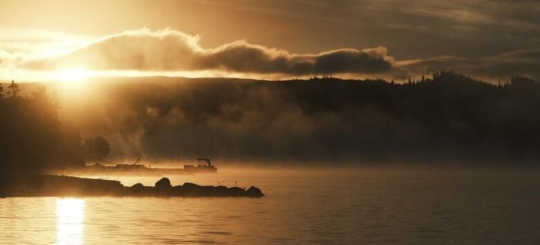 Sunrise over a misty lake.