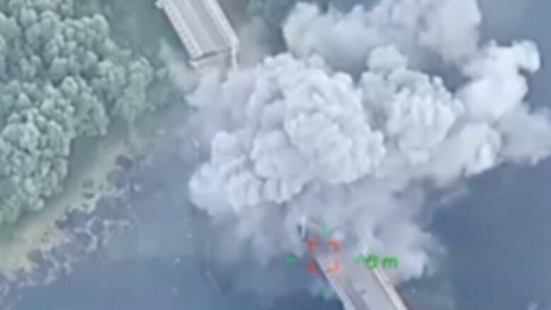 Smoke billows from a bridge that was bombed.