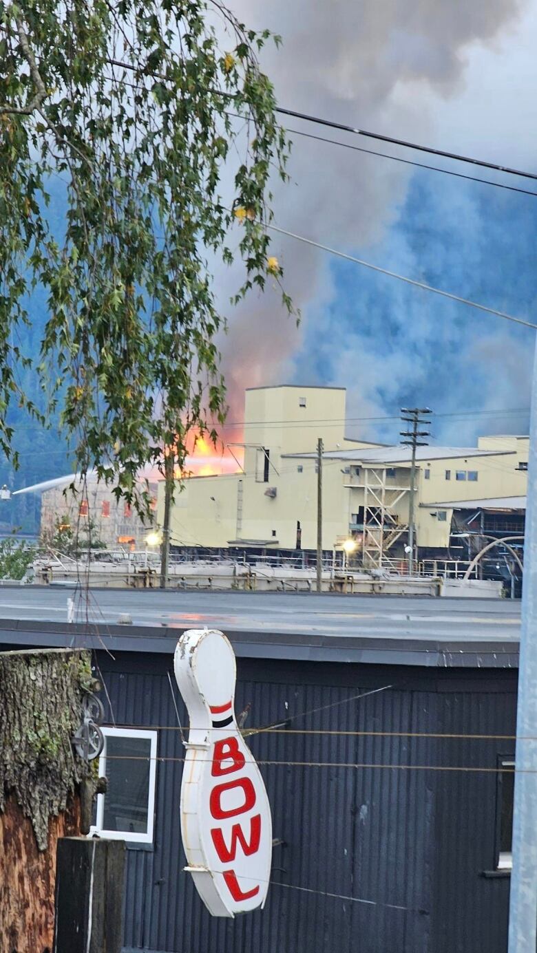 A fire is seen in the distance among various buildings, with a bowling alley in the foreground.