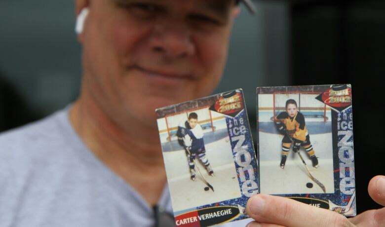 A person holds up two hockey cards