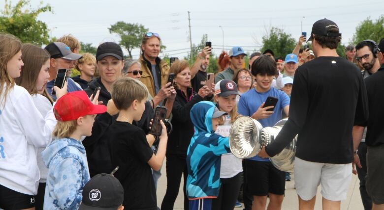 A bunch of people hold up their phones toward the stanely cup