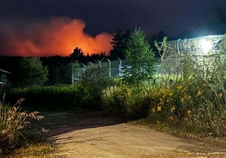 An outdoor photo with a bright red light and smoke coming from the distance