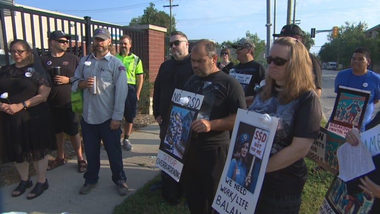 A group of people hold signs during a protest against Canada Post on a sidewalk. 