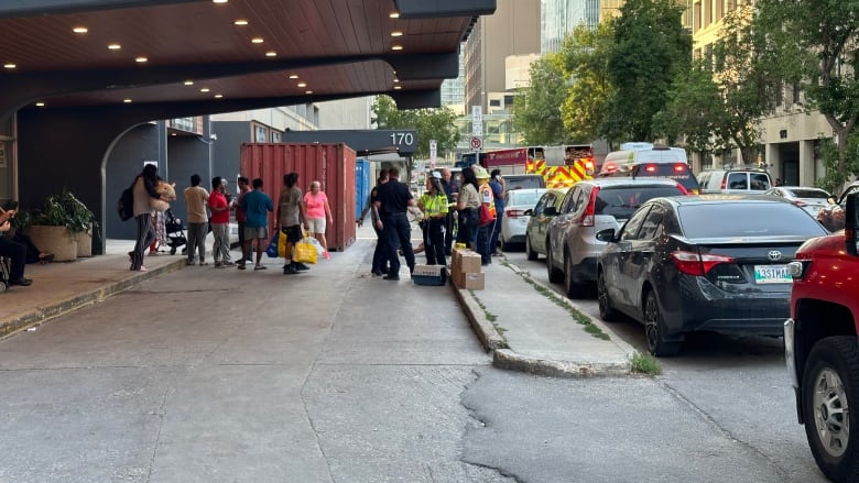 People holding their personal belongings exit a building. 