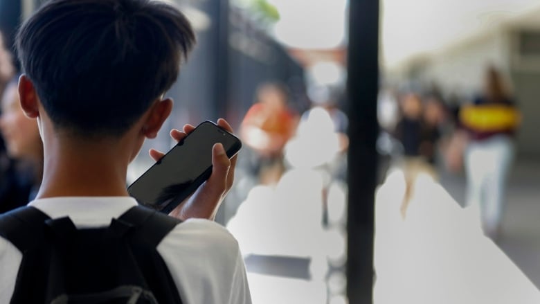 Shot from behind of a student holding a cell phone