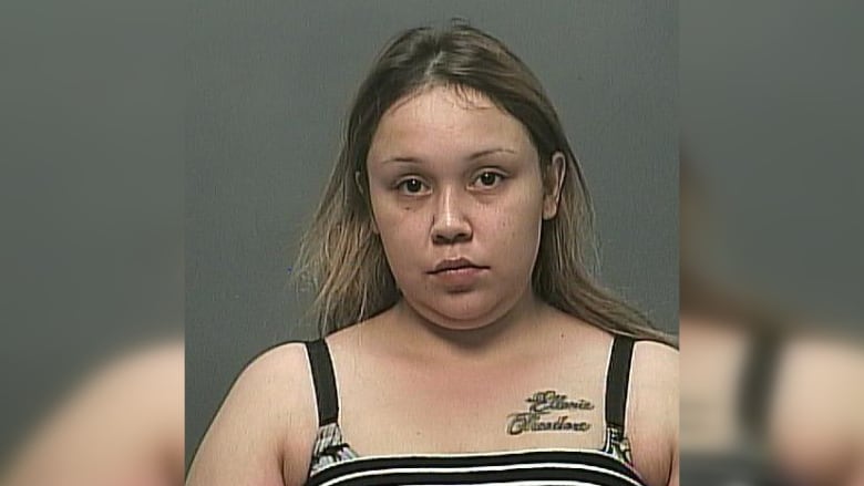 A police mug shot of a woman who has long hair and wears a striped top.