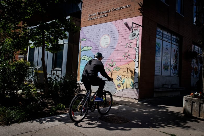 A man bikes past a health centre building.