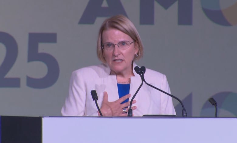 A politician gestures to her heart while making an announcement at a conference.