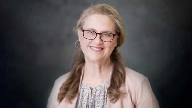 Woman with pink sweater and glasses.