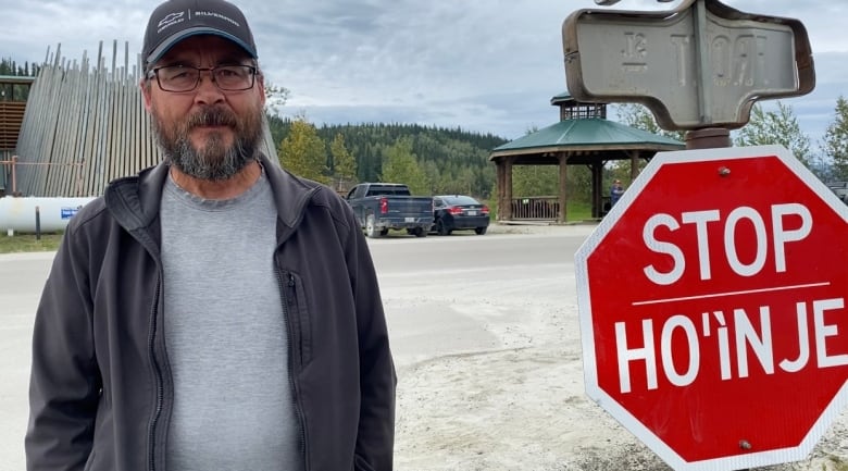 A man standing beside a stop sign.