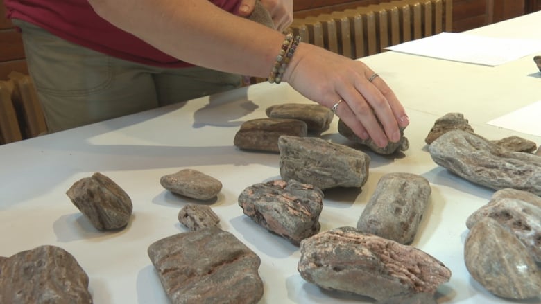 A woman's hand touches wood that looks like rock.