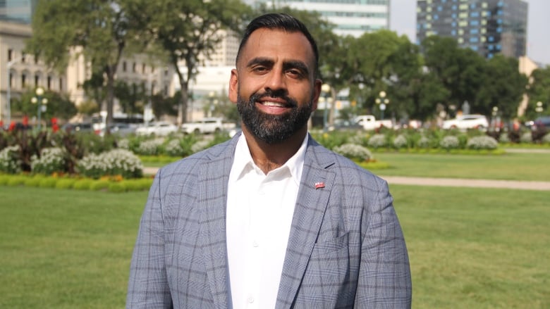 A man in a checkered suit and a white shirt stands on a lawn.