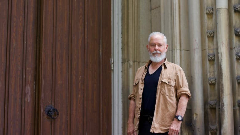 A person stands before a stone church with a big wooden door. 