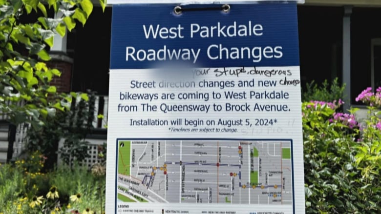 A poster noting road changes for a bike lane is defaced. It reads: 