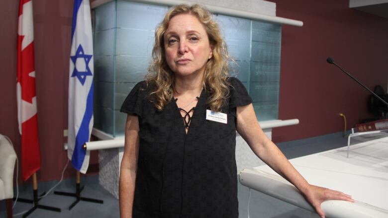 A woman in a black blouse stands in a synagogue.