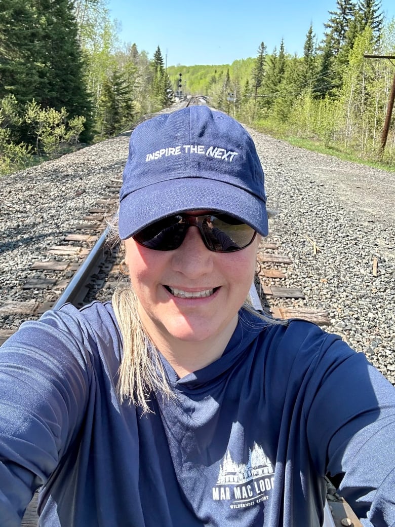 A woman dressed in blue standing on a train track.