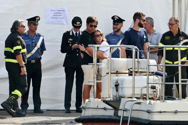 Several people are shown on what appears to be a dock, near a seacraft.