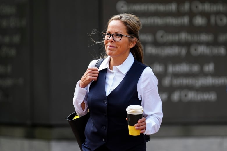 A woman walks near a courthouse in a city in summer.