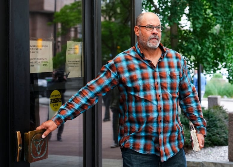 A man pulls on a courthouse door in summer.