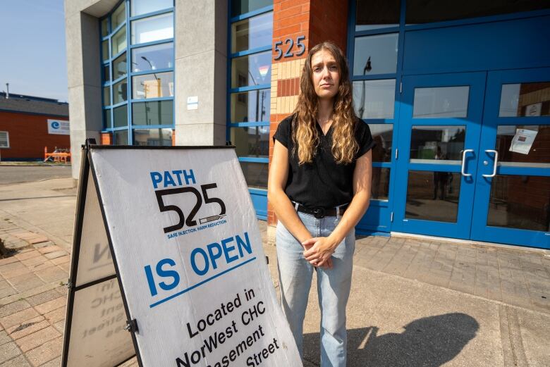 A person is seen standing outside beside a sign that says 