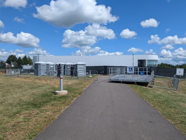 An accessible platform with portable toilets sitting adjacent on a lawn. 