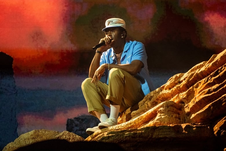 A man sits on stage holding a microphone. 