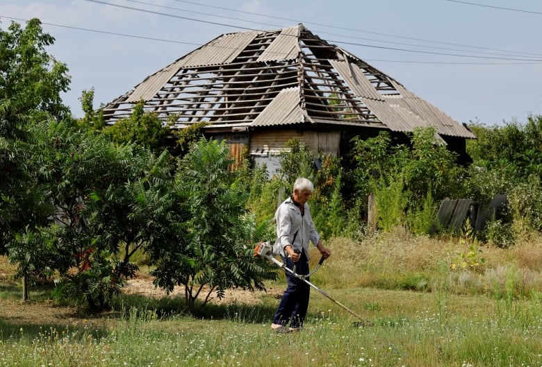 A man uses a landscaping lawn-trimmer near a damaged home in Bobrove, Ukraine, on Friday.