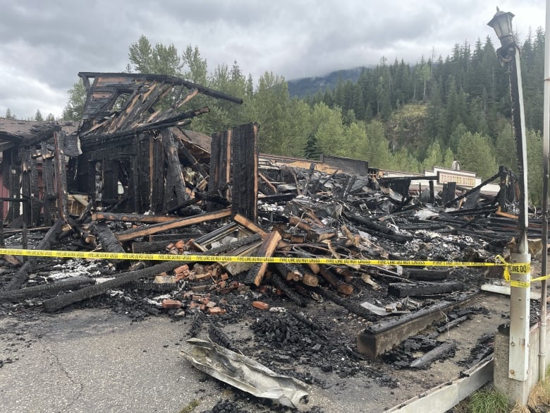 A burned down structure is secured with yellow tape