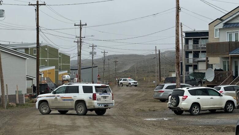 RCMP vehicles on a street outside with houses along the side 