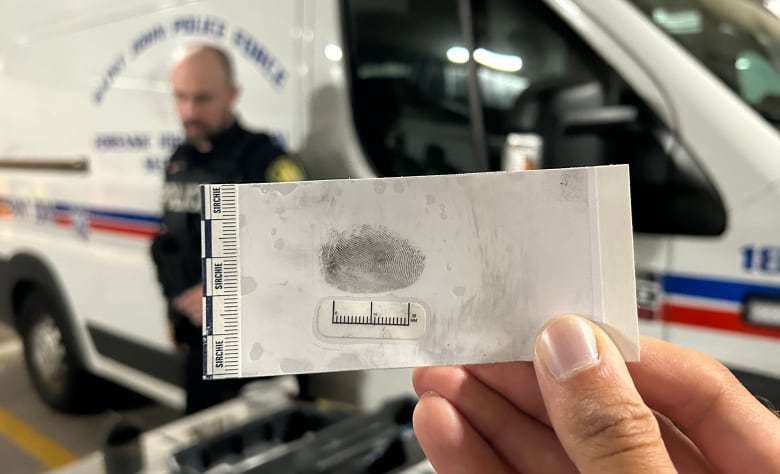 A hand holding a paper with a fingerprint.