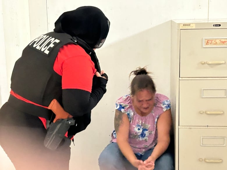 A lady crying and a lady dressed in police uniform helping her.