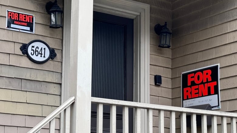 A for rent sign is shown on the front of a home with beige siding and a white fenced deck.