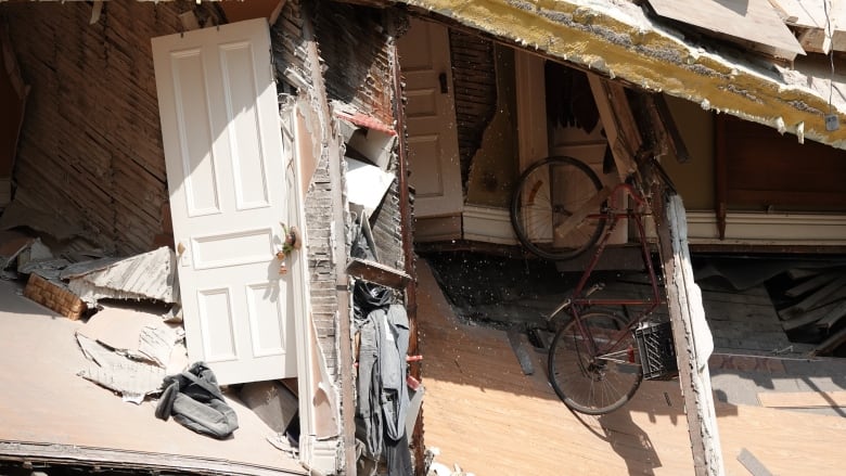 A red bicycle hanging vertically amid debris.