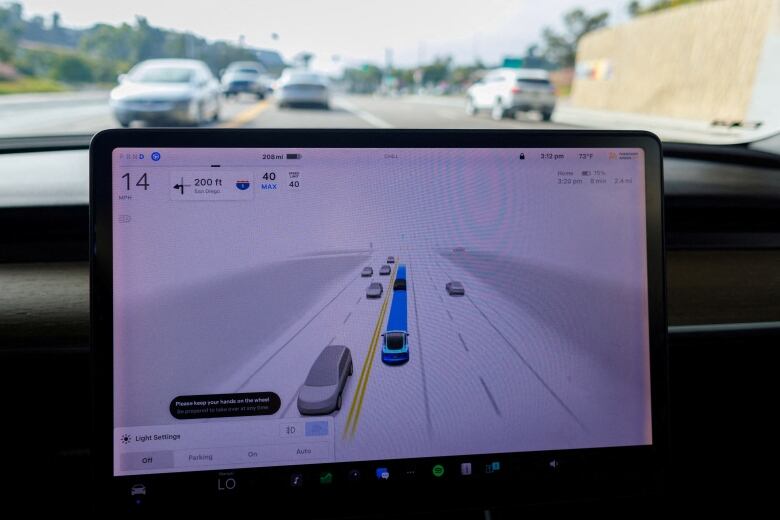 The interior of a car, with a screen for self-driving cars displayed. In the background, blurry cars on the highway are visible. 