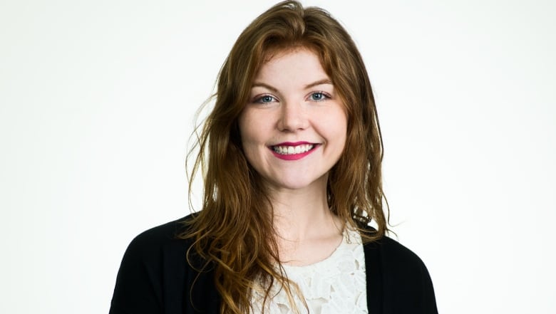 A smiling woman with red hair in front of a white background